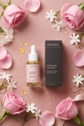 Flat lay of ENTEE Nourishing Facial Oil bottle and box on blush pink with rose petals